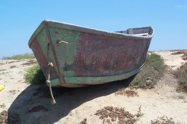 a small boat sitting on a beach by the water