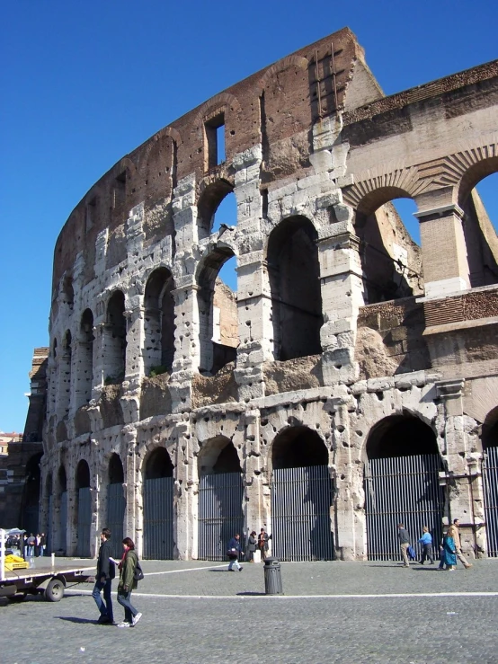 several people walk in front of a very old looking building