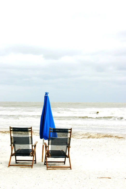 a couple of chairs sitting under a blue umbrella