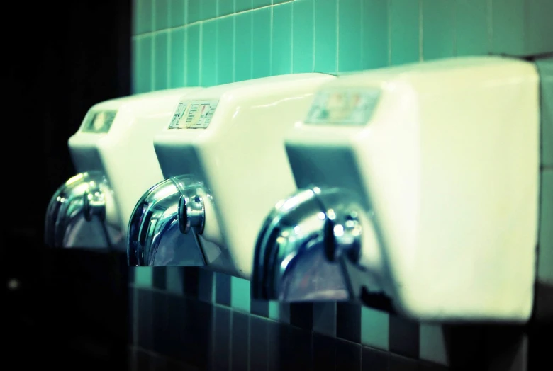 three urinals hanging on a tiled wall