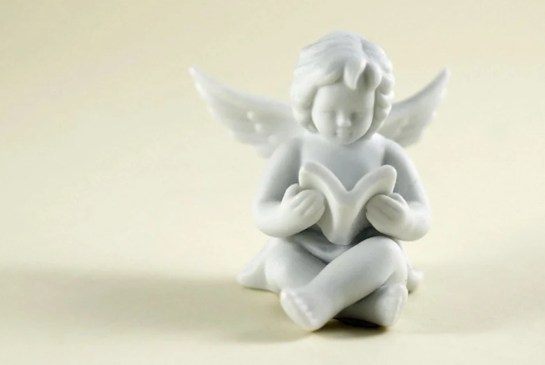 the small ceramic angel is reading a book