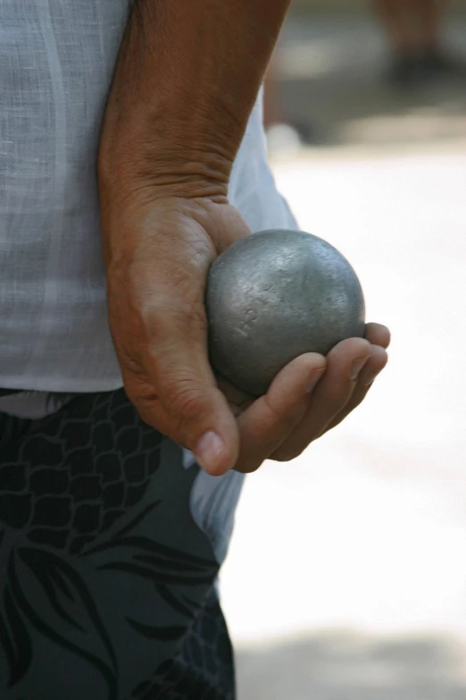 a man holds a metallic ball in his hand