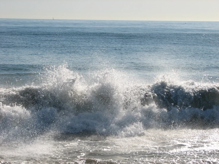a large wave crashing towards the shore on a beach