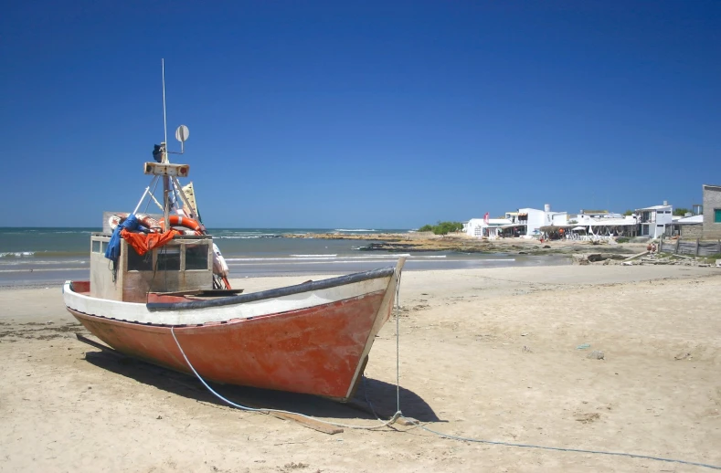 a small boat sitting on the sand at the beach