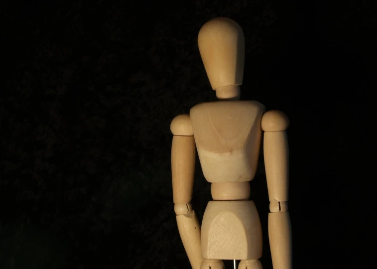 wooden dummy wearing brown clothing with black background