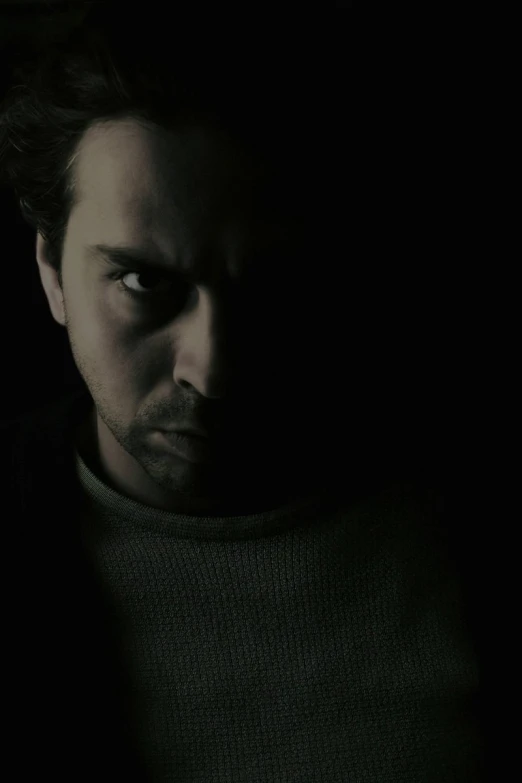 a man staring at the camera in dark light