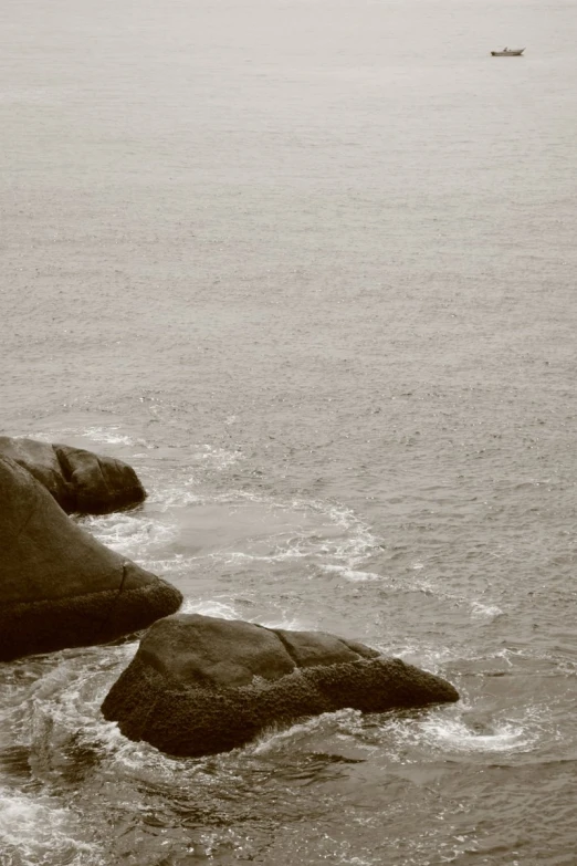 two rocks and some water with a boat in the distance