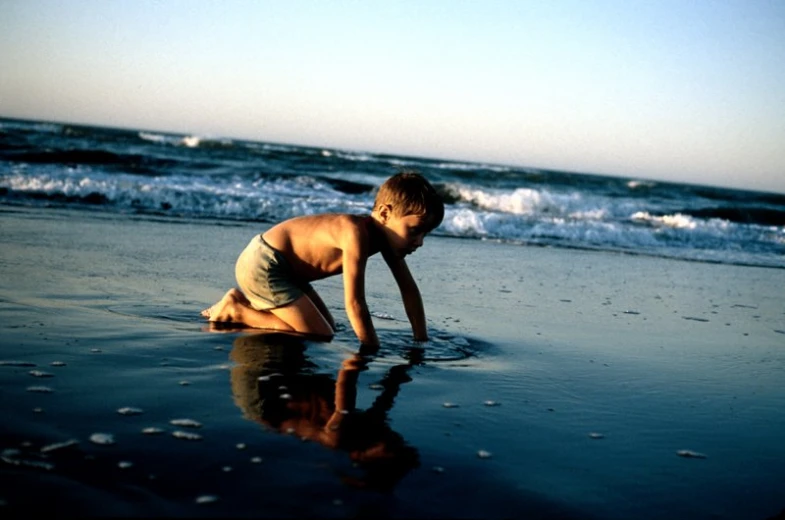 a small boy plays in the shallow water