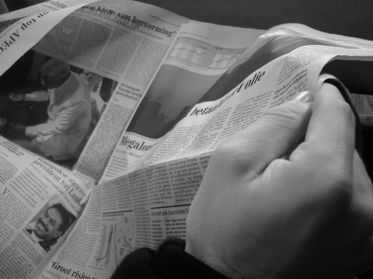 person holding up many newspapers and reading it