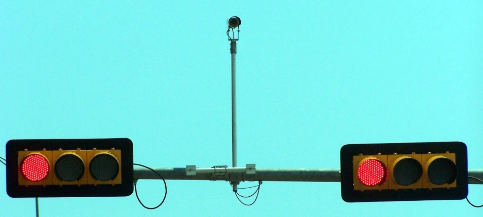 two red stoplights with a pole and a light above