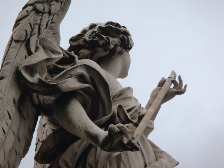 a statue holding a pipe near a statue of an angel