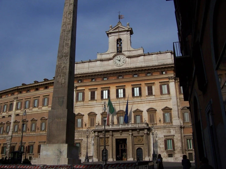 the obelisk stands at one end of the courtyard in front of a large building