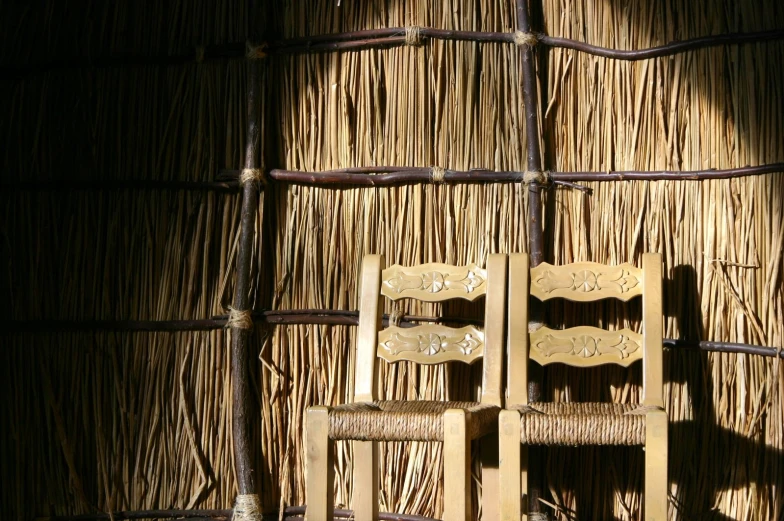 the back of a bamboo house, with two wooden chairs