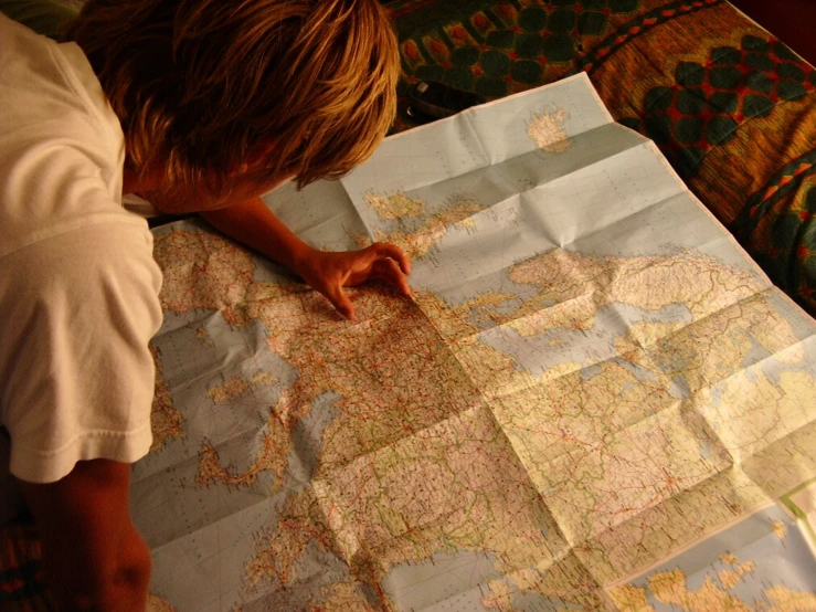 the boy is looking at his map as he writes