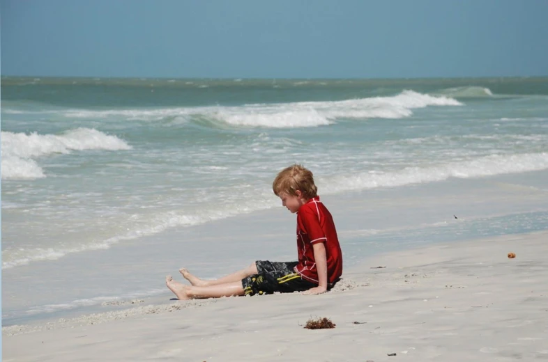 a  wearing a wet suit sitting on the beach