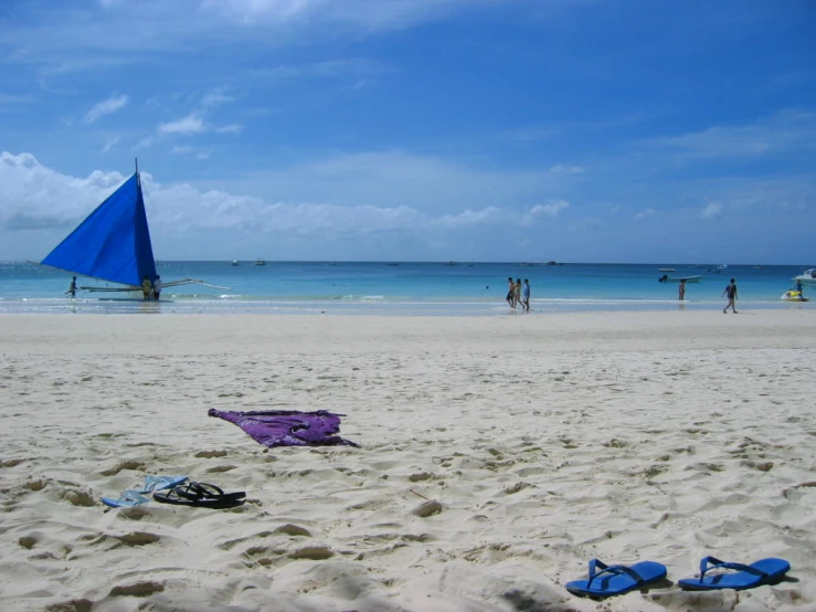 a sail and sandals on the beach near the water