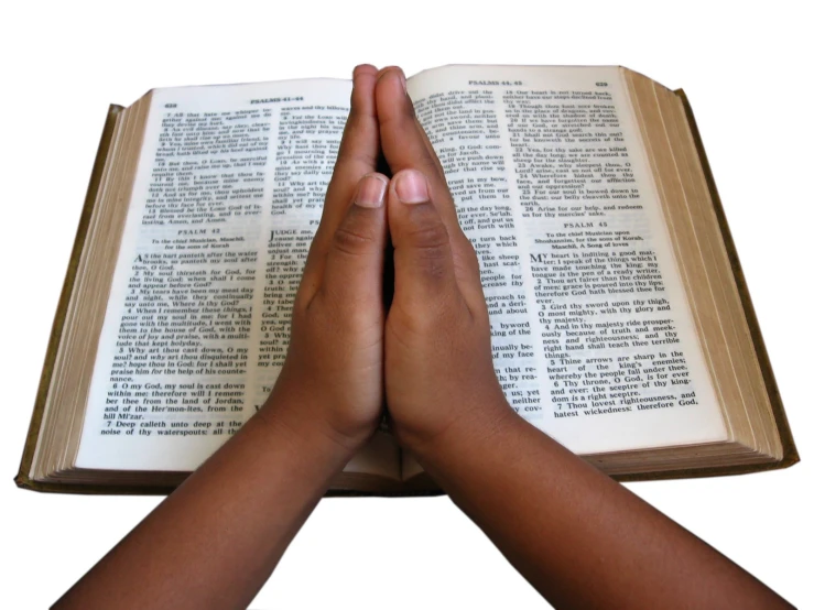two hands holding an open book with the word of god
