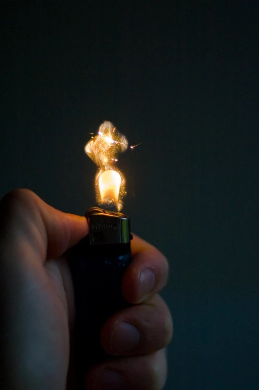 a man holding a lighter lite up in the dark