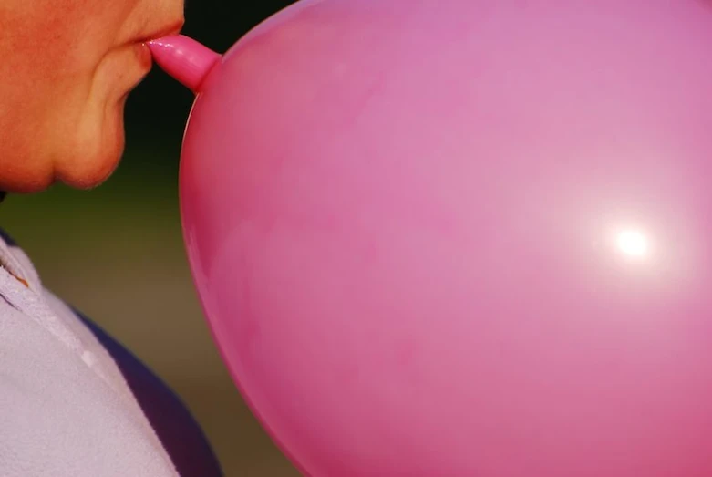 woman with bubble attached licking pink ballon