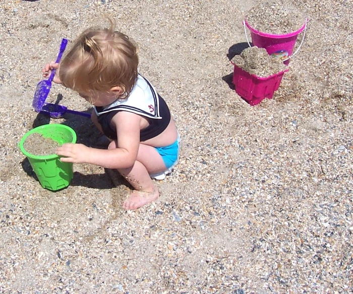 a baby playing with sand on the beach