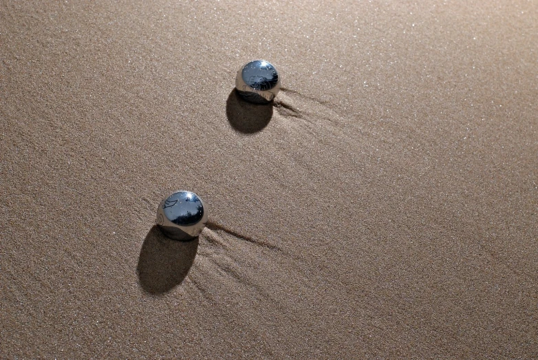 two small rocks are in the sand of the beach