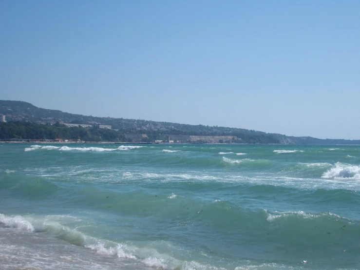 waves rolling in towards shore with a hill in the background