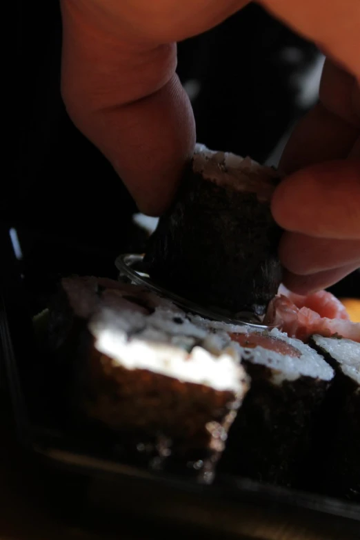 someone cuts some sushi on a small plate