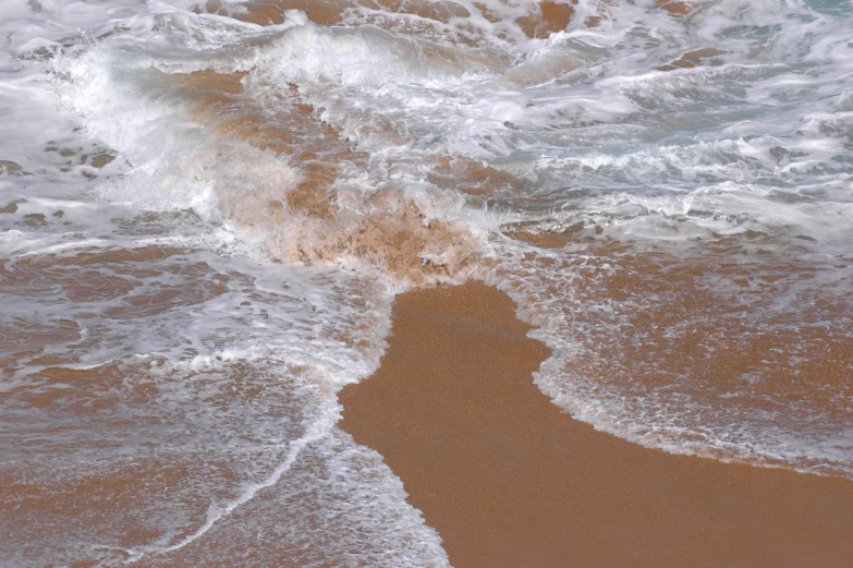 an aerial s of waves crashing in on the sandy shore