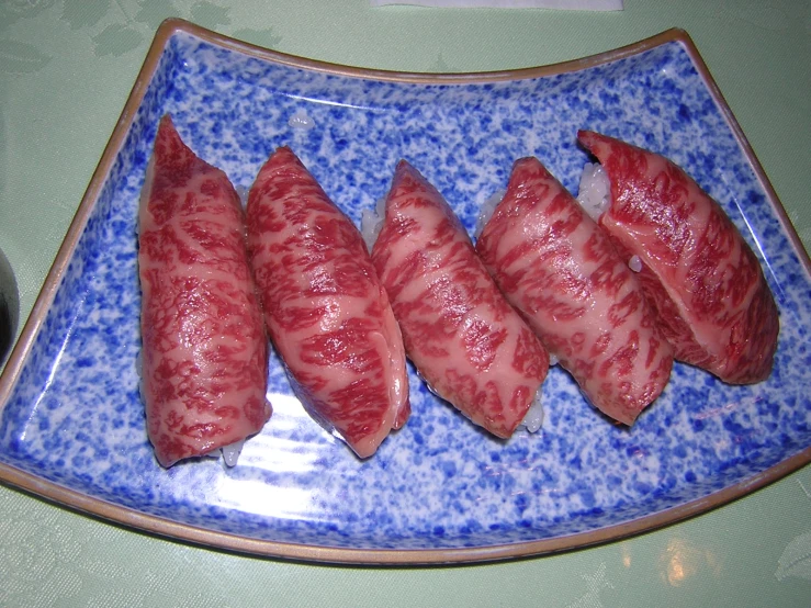 sliced raw meat displayed on blue and white plate