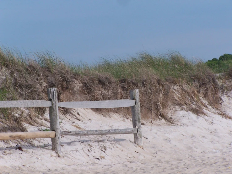 a wooden fence in sand near some dunes