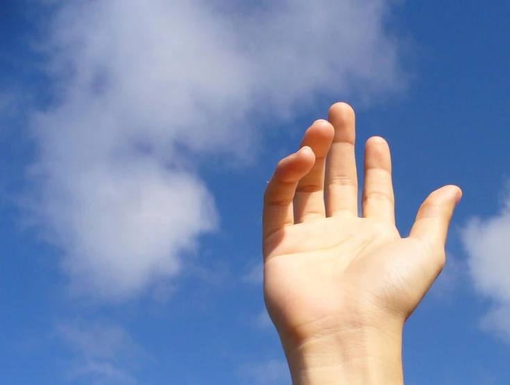 a hand that is reaching for a fly kite in the air