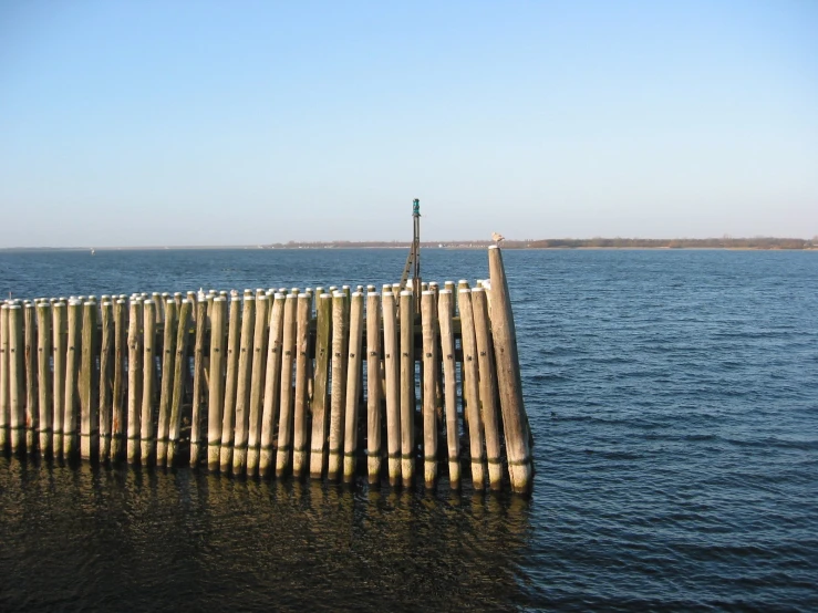 a wooden fence next to the water on a sunny day