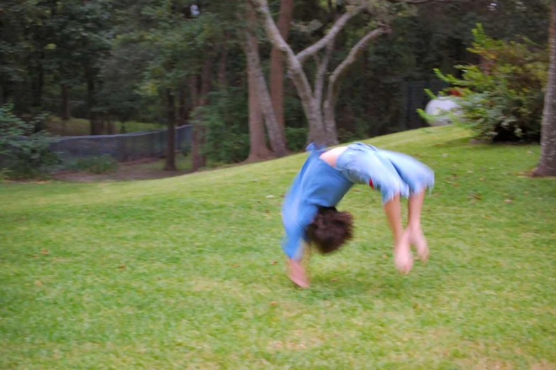 the person with their head in the grass has one leg back to the ground