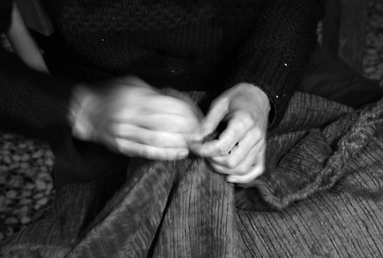 a person knitting soing while sitting on a chair