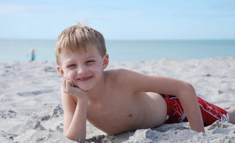 a  laying on the beach in his swimming trunks