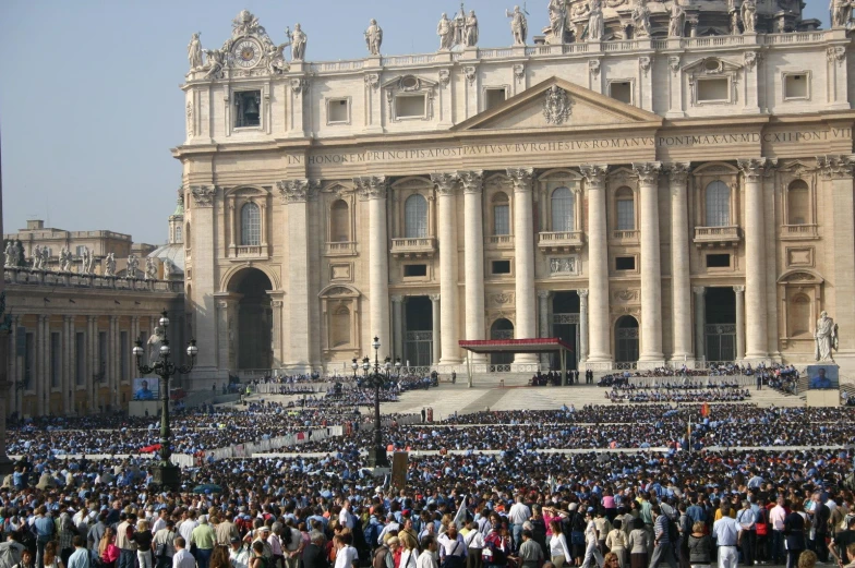 a large crowd in front of a church with a statue