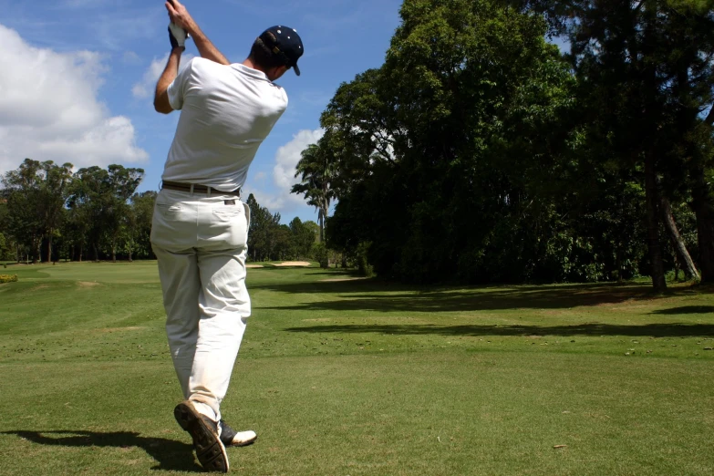 a person swinging a golf club on a green