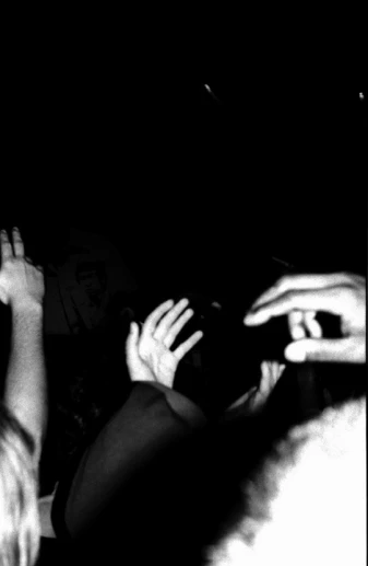 a person is waving his hands up at someone on a dark background