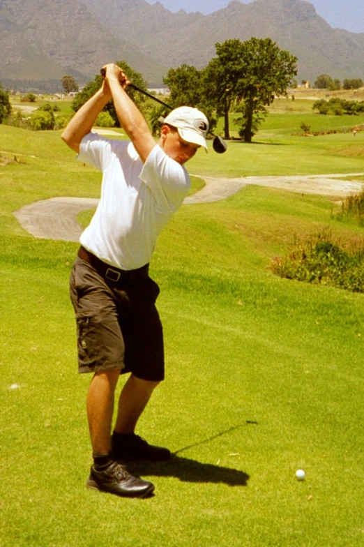 a man hitting a golf ball in the grass