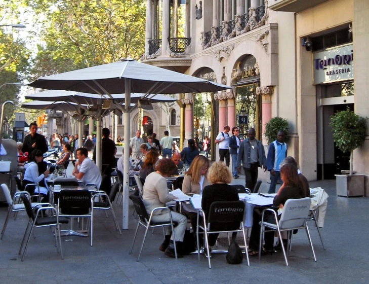 people are eating outside under umbrellas near shops