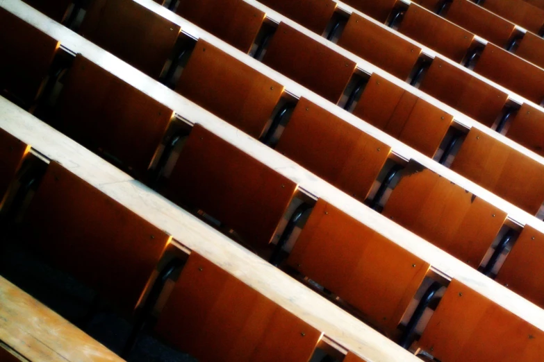 rows of brown and white wooden seats in an auditorium