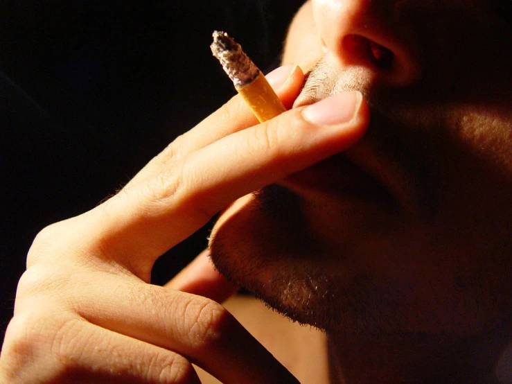 a man smoking a cigarette with his shadow on the wall