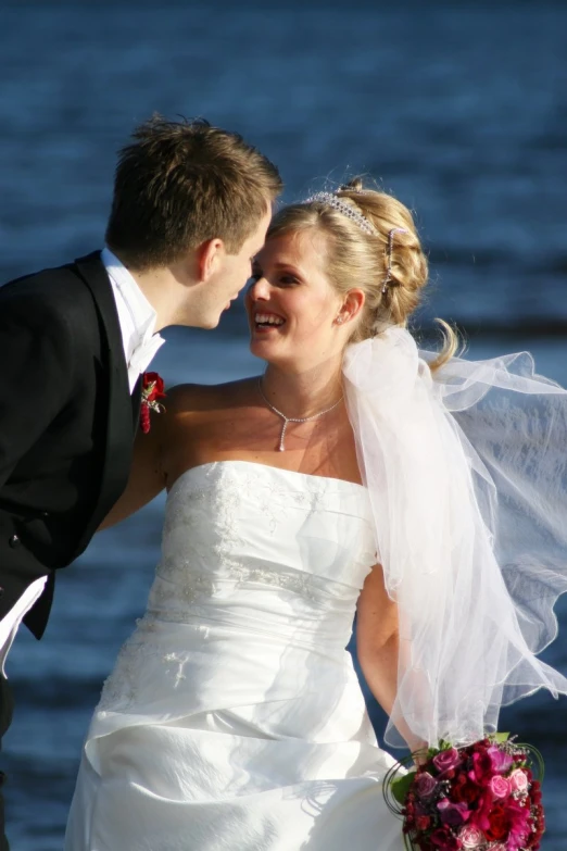 a bride and groom standing near water during a wedding po