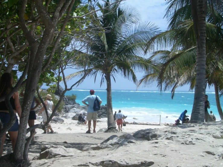 people walk along a sandy beach in a blue lagoon