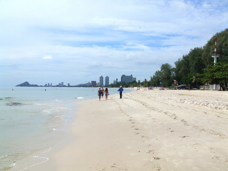 people are walking along a beach with clear water
