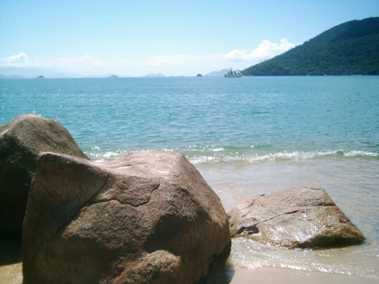 two rocks laying on the beach near an ocean