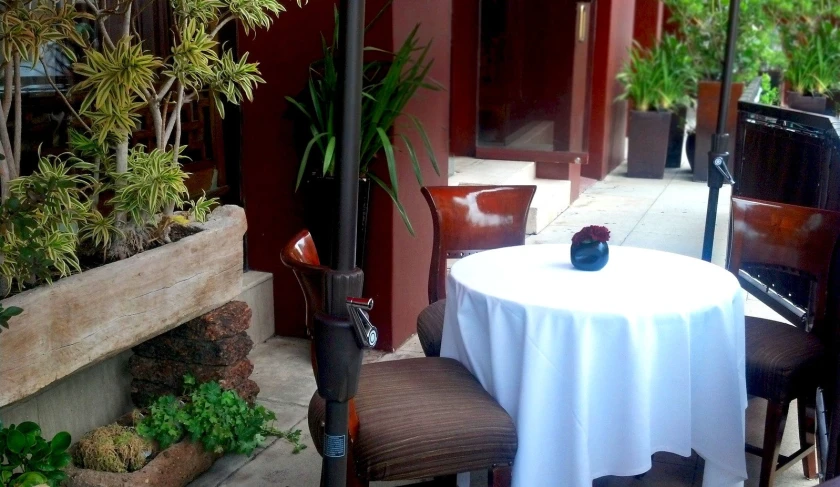 an outdoor patio with table and chairs with umbrella over it