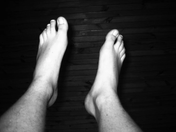 black and white pograph of two feet and the upper half of a person