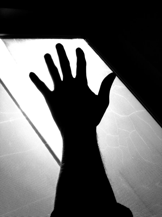 a hand is being cast in the air near a window