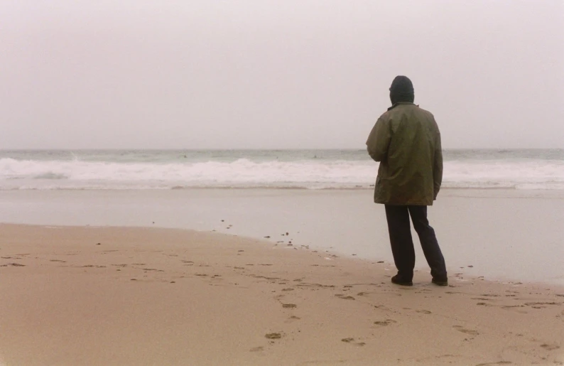 a man is standing alone in the sand near the ocean